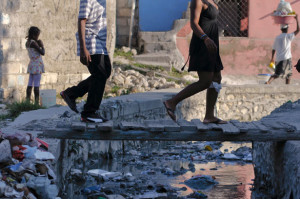 People walk across a tiny overpass as raw sewage flows beneath in an open sewage in Port-au-Prince September 4, 2012. REUTERS/Swoan Parker 