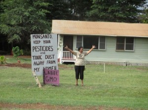 A Molokai resident expresses joy as the march passes by her home, which is located across the street from Monsanto’s fields. (WNV/Imani Altemus-Williams)