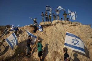 Israeli settler youths wave Israeli flags at the start of a protest march against Palestinian statehood, from the West Bank Jewish settlement of Itamar near the Palestinians town of Nablus. (AP Photo/Ariel Schalit, File)