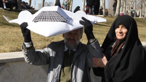 An Iranian couple hold a model of the captured US RQ-170 drone during the 33rd anniversary of the Islamic revolution in Azadi (Freedom) square in Tehran on February 11, 2012. (AFP Photo/Atta Kenare)