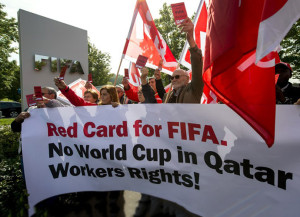 Members of Building and Wood Workers' International (BWI) and Swiss Unia unions hold a red cards reading "A red card for FIFA, no World Cup without labour rights" and a banner reading "No World Cup in Qatar Workers Rights!" during a demonstration outside the headquarters of the world's football governing body FIFA in Zurich on October 3, 2013.  (AFP Photo/Fabrice Coffrini)