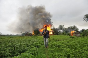 An ethnic Rakhine man with homemade weapons walks near houses that were set aflame during fighting between Buddhist Rakhine and Muslim Rohingya communities in Sittwe, Burma, on June 10. (Reuters)