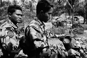 Photograph by Greg Constantine Two members of a notoriously vicious Buddhist security force patrol a  camp outside Sittway, the capital of Arakan.