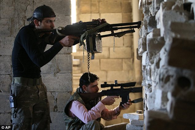 Fighting back: Free Syrian Army fighters take their positions as they observe official Syrian army forces base of Wadi al-Deif, at the front line of Maaret al-Numan town, in the Idlib province