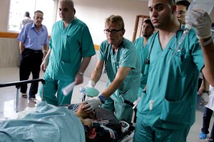 Dr Mads Frederick Gilbert (centre) at Al-Shifa hospital on July 17 2014, treating a wounded Palestinian child, after an Israeli air strike killed 4 children and wounded 5 others.