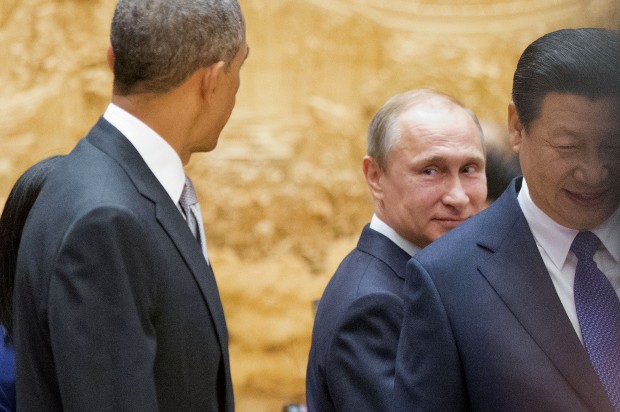 Russian President Vladimir Putin, center, looks back at US President Barack Obama, left, as they arrive with Chinese President Xi Jinping, right, at the the Asia-Pacific Economic Cooperation (APEC) Summit plenary session at the International Convention Center, Yanqi, Tuesday, Nov. 11, 2014 in Beijing. (AP Photo/Pablo Martinez Monsivais, Pool) (Credit: Pablo Martinez Monsivais)