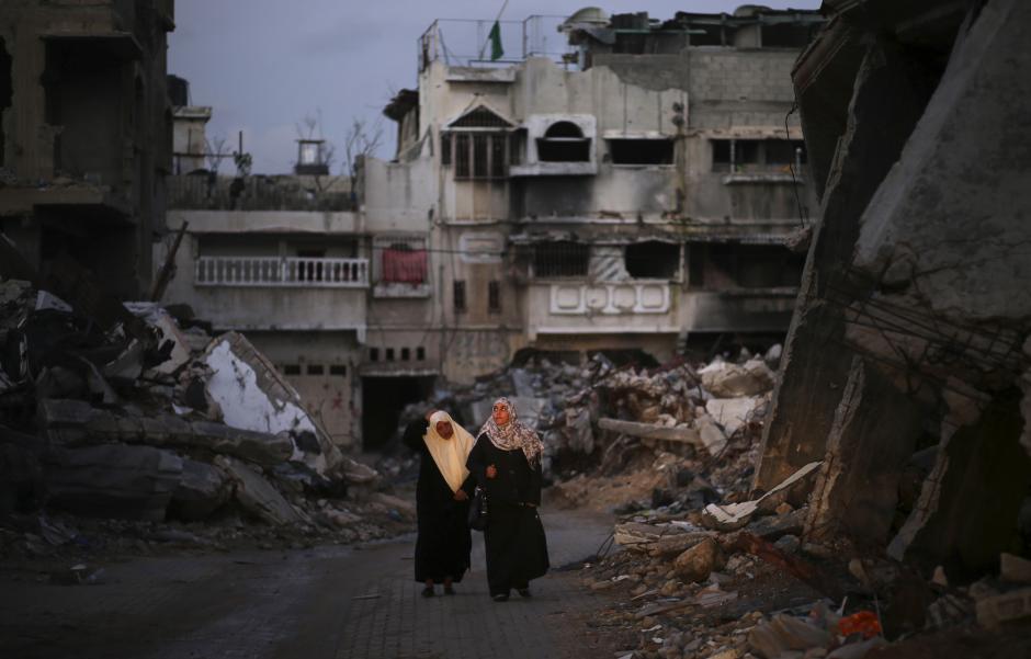 Palestinian women walk near the ruins of houses, which witnesses said were destroyed by Israeli shelling during the most recent conflict between Israel and Hamas, in the east of Gaza City December 1, 2014. Mohammed Salem/Reuters