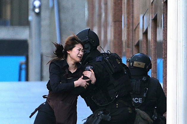 A hostage runs to armed tactical response police officers for safety after she escaped from a café under siege in Sydney, Australia, on Dec. 15.