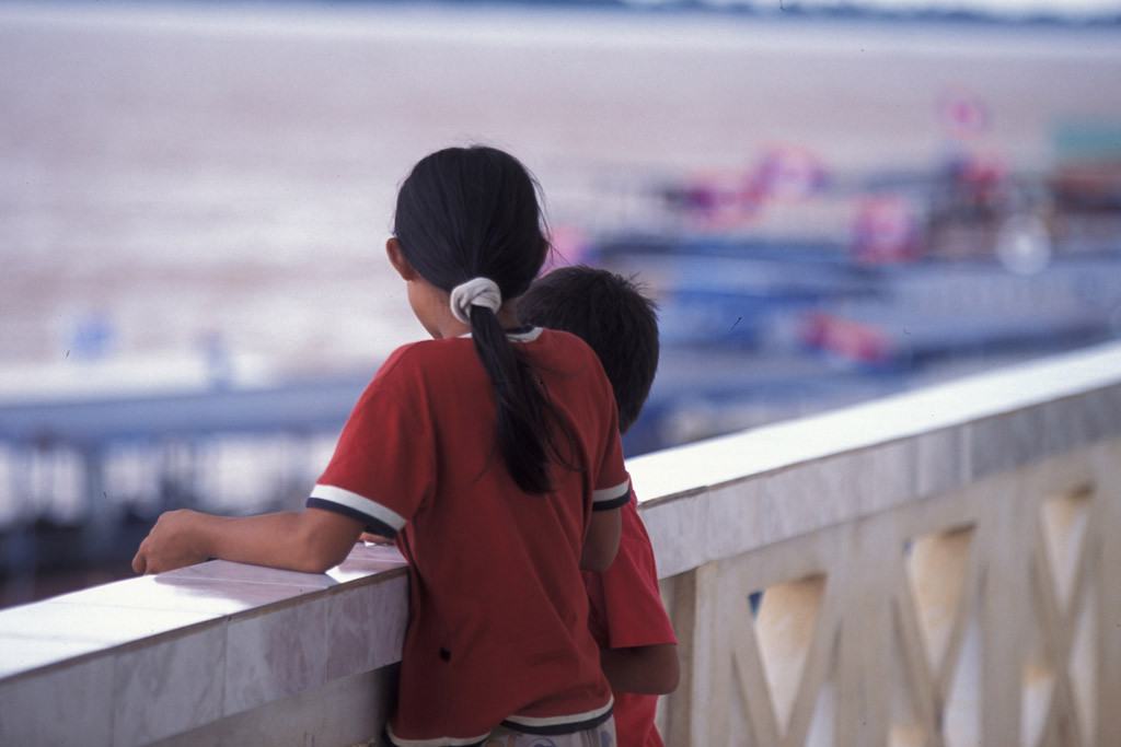 Two children stand on the balcony of an immigration office in Laos. The UN Children’s Fund (UNICEF) works with the Government and partners to stem the flow of young people into dangerous labour agreements outside the country. Photo: UNICEF/LaoPDR04713/Jim Holmes