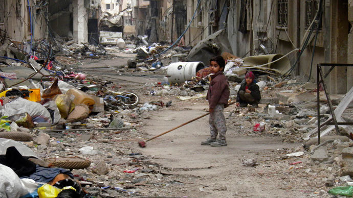 A child clears damage and debris in the besieged area of Homs (Reuters / Thaer Al Khalidiya)