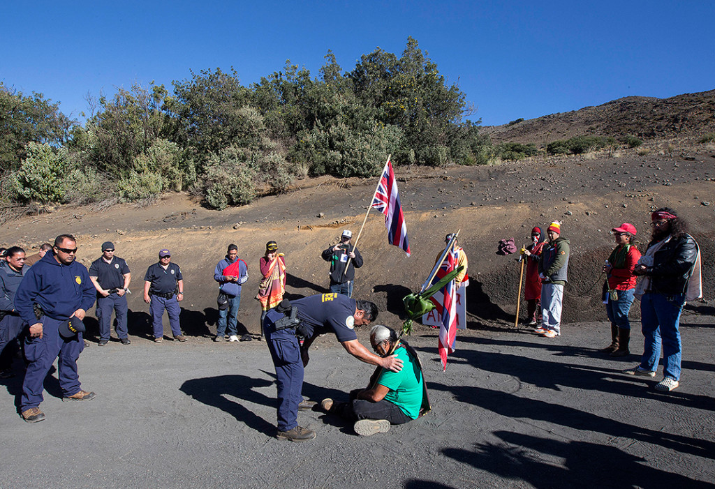 Protesters have for the past three weeks created a human blockade. More than 30 people have been arrested. On April 2, 2015, a Department of Land and Natural Resources Officer speaks with one of the activists. (AP Photo/Hawaii Tribune-Herald, Hollyn Johnson)