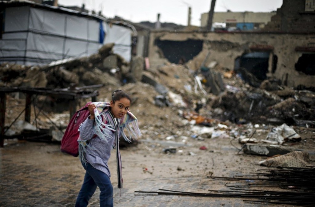  A Palestinian schoolgirl walks past the rubble of a house that witnesses said was destroyed by Israeli shelling during a 50-day war in 2014 summer, on a rainy day in Beit Hanoun town in the northern Gaza Strip April 12, 2015. (REUTERS/Suhaib Salem)