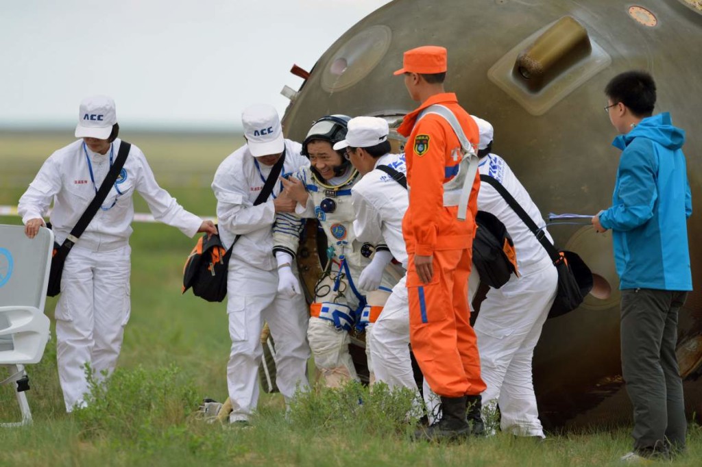 Chinese astronaut Nie Haisheng (5th R) gets out of Shenzhou-10 spacecraft that landed on the grasslands of north China's Inner Mongolia region on June 26, 2013, after a 15-day mission in space. China completed its longest manned space mission on June 26 as its Shenzhou-10 spacecraft and three crew members safely returned to Earth, in a major step towards Beijing's goal of building a permanent space station by 2020.   CHINA OUT     AFP PHOTO        (Photo credit should read STR/AFP/Getty Images)