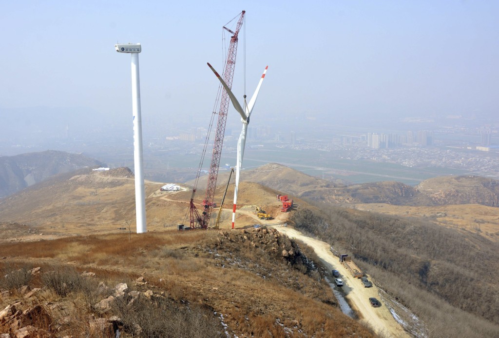 The rotor blades of a wind turbine is lifted by a crane at a construction site of a wind power plant in Yiyang, Henan province, China, February 10, 2015. China's wind farm firms are feeling the heat as state grid operators deliberately delay hooking them up and cut back on purchases, wasting about a fifth of the total wind power output or enough electricity to run Beijing for 40 days. Picture taken February 10, 2015. REUTERS/Stringer 