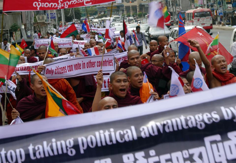 Buddhist monks holding placards shout slogans as they march for a protest Wednesday, Feb. 11, 2015, in Yangon, Myanmar. Hundreds of people have demonstrated in Yangon, Myanmar's biggest city, to protest a government decision to allow people without full citizenship, including members of the Rohingya ethnic minority, to vote in an upcoming constitutional referendum. Parliament recently decided to allow temporary identity card holders, known as white card holders, the right to vote in a referendum for constitutional amendments. (AP Photo/Khin Maung Win)