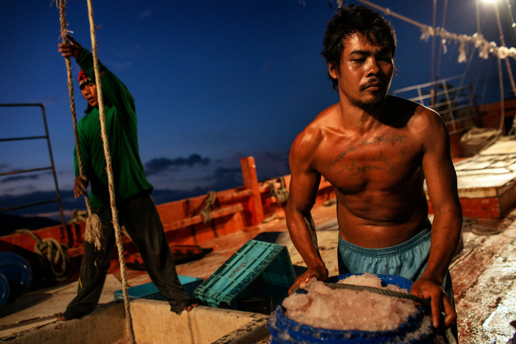 Migrant workers unloaded barrels of fish at the docks in Songkhla. "Motherships" bring the catch to shore so that the trawlers can stay at sea. Credit Adam Dean for The New York Times.