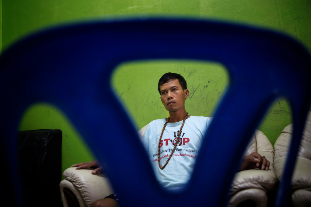 Lang Long, 30, watched television in a safe house in Songkhla. Mr. Long, a Cambodian, was rescued from a fishing boat where he was forced to work on for three years and was often restrained with shackles. Credit Adam Dean for The New York Times