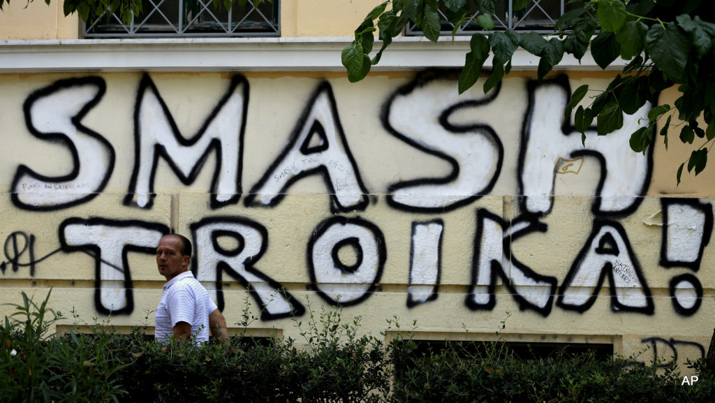 A pedestrian passes graffiti referring to the officials from the European Union, European Central Bank and International Monetary Fund, together known as the troika, in Athens, Wednesday, July 29, 2015. Representatives of Greece’s creditors, its European Union partners and the International Monetary Fund, are currently meeting officials in Athens to discuss the terms of the new bailout, designed to provide 85 billion euros over three years. (AP Photo/Thanassis Stavrakis)