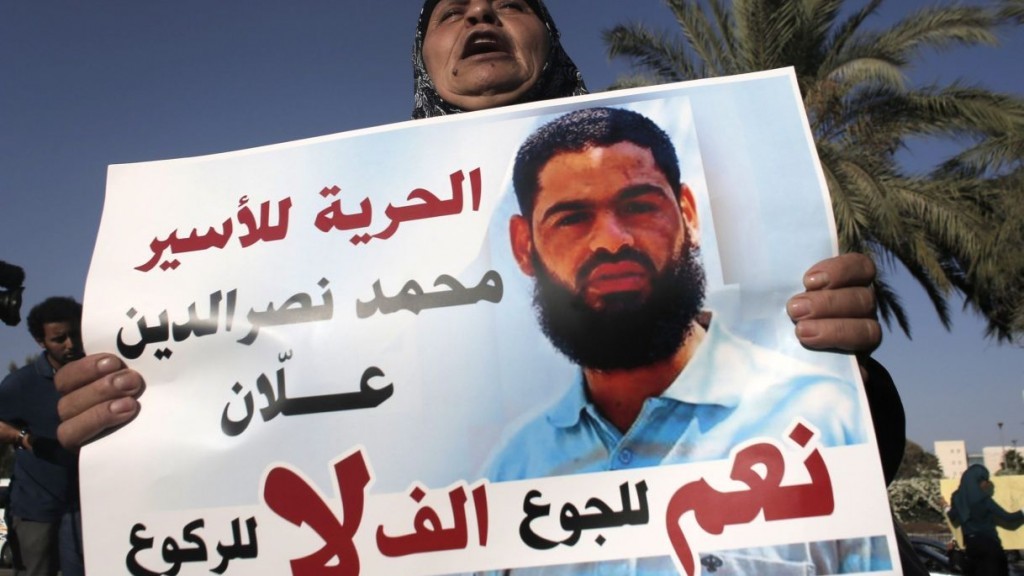 The mother of Mohammed Allan, a Palestinian prisoner who is on a long-term hunger strike, holds a portrait of her son during a rally calling for his release, Be’er Sheva, Aug. 9, 2015. AFP