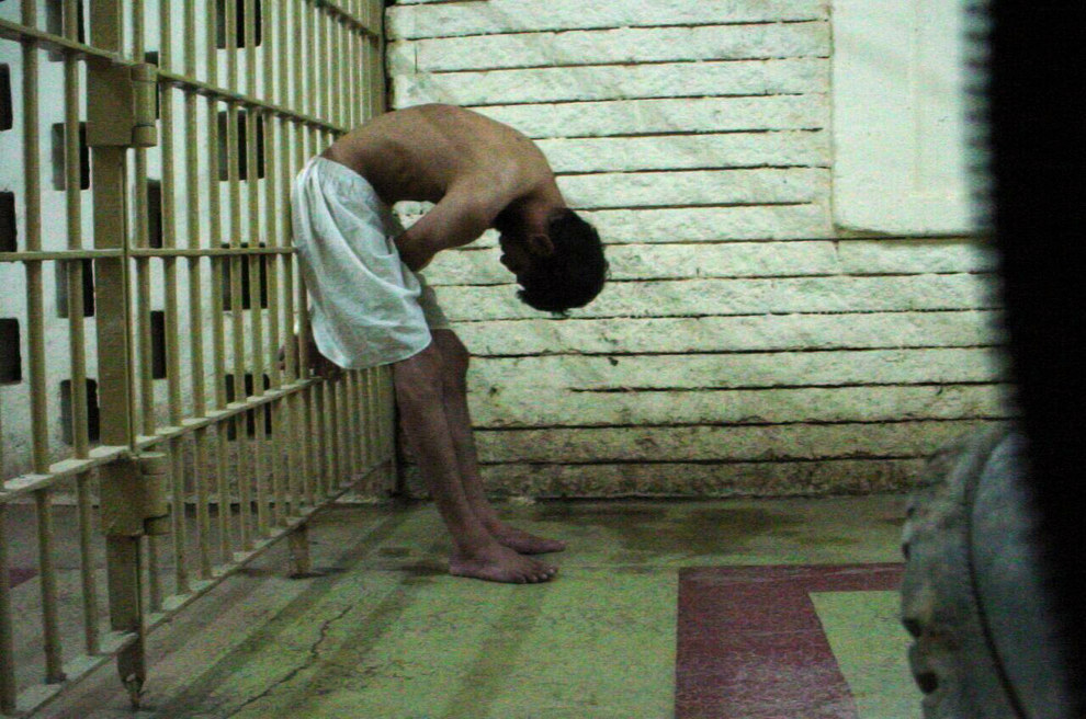 A detainee bent over with his hands on the bars of a prison cell at the Abu Ghraib prison in Baghdad in 2003. Associated Press / Via apimages.com