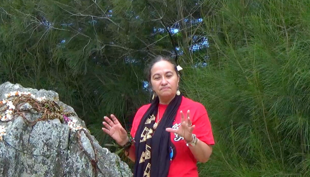 Pua Case standing next to the sacred rain rock in Waimea, Hawaii. Credit: Shannon Biggs. Some rights reserved.