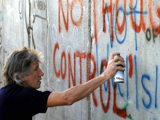 Roger Waters alludes to the band’s lyrics while painting on the Israeli-Palestinian security barrier in Bethlehem in 2006 (Getty)