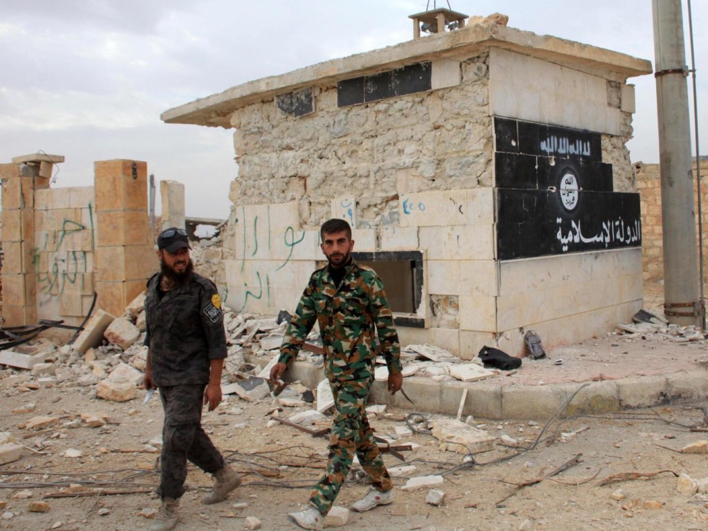 Government troops walk past Isis flag in recaptured Syrian town Getty Images