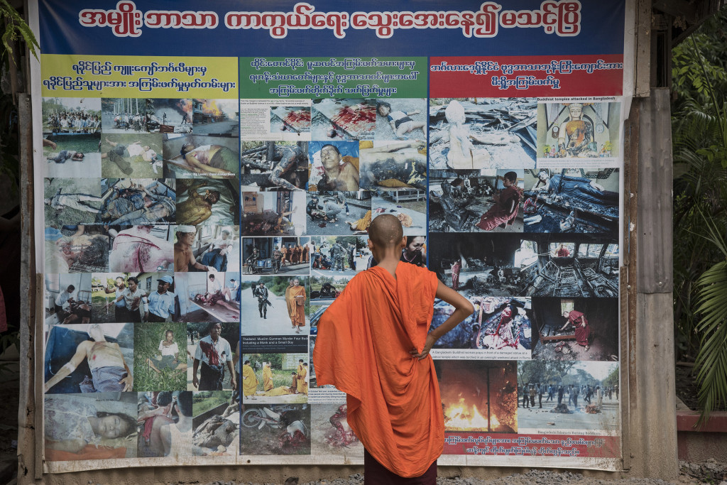 MANDALAY, MANDALAY REGION, MYANMAR - 2015/05/24: A young Buddhist novice looks at a panel filled with pictures showing atrocities allegedly committed by Muslims against Buddhists. This panel is erected in front of Buddhist monk Wirathu's quarters at Ma Soe Yein monastery (Mandalay). Wirathu is considered as a leader of a Myanmar radical Buddhist nationalist movement professing strong anti-Muslim propaganda. (Photo by Thierry Falise/LightRocket via Getty Images)