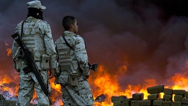 Two soldiers watch 134 tonnes of marijuana burning in the border town of Tijuana, Mexico. | Photo: AFP