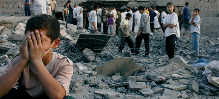 An Iraqi boy covers his face with his hands while weeping as people survey the destruction in a neighborhood following a US airstrike. (photo: Faris DLIMI/AFP)