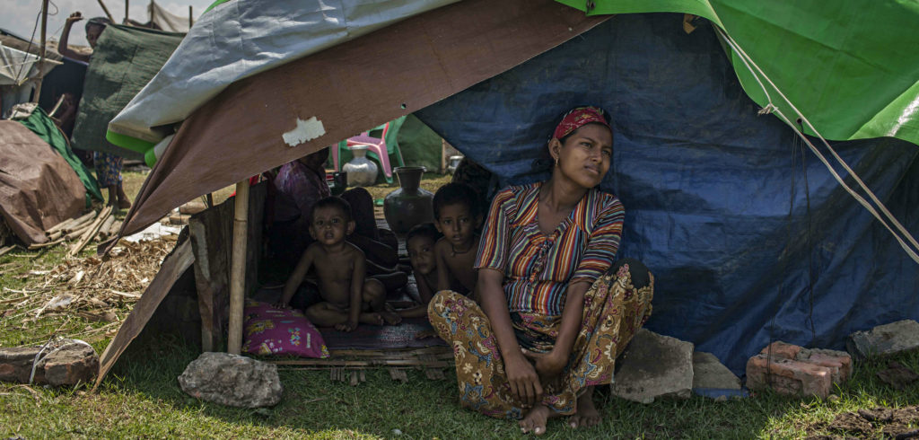 A Rohingya woman sits with her children in their temporary shelter next to the Baw Du Pha internal displacement camp on May 17 in Sittwe, Burma. Photo credit: Lauren DeCicca/Getty Images