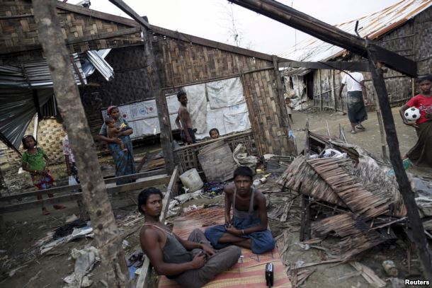 FILE - Rohingya people pass their time in a damaged shelter in Rohingya IDP camp outside Sittwe, Rakhine state, Aug. 4, 2015.