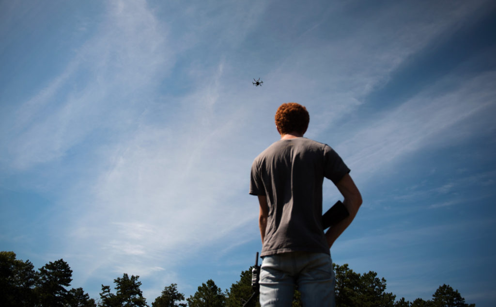 Jacob Regenstein, an engineer, held a fake rifle during a test of an autonomous drone in August on Cape Cod, in Massachusetts. Credit Hilary Swift for The New York Times