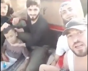 U.S.-backed Syrian “moderate” rebels smile as they prepare to behead a 12-year-old boy (left), whose severed head is held aloft triumphantly in a later part of the video. [Screenshot from the YouTube video]