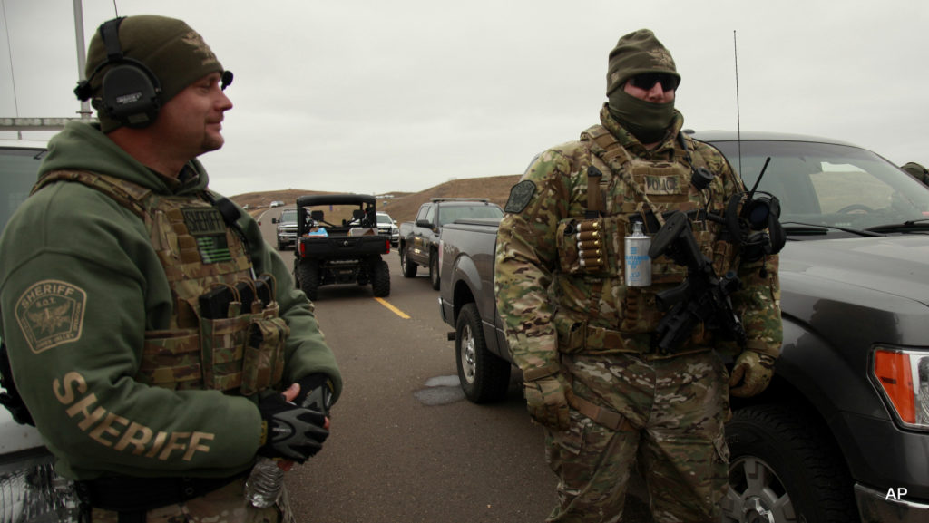 Members of the Stutsman County SWAT watch protesters demonstrating against the Dakota Access Pipeline near the Stand Rock Sioux Reservation, as they stand next to a police barricade on Highway 1806 in Cannon Ball, N.D., Sunday, Oct. 30, 2016.