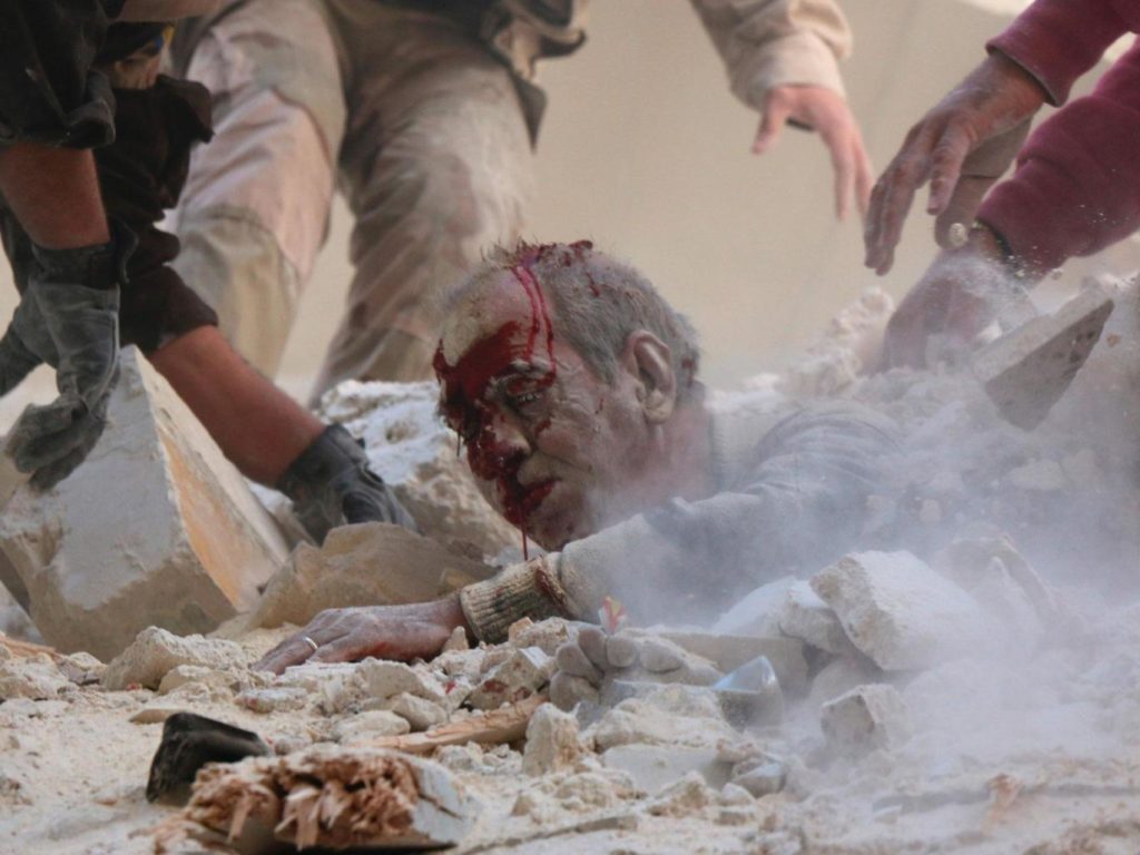 Syrian rescue workers and residents try to pull a man out from under the rubble of a building following a reported air strike on the rebel-held neighbourhood of Salhin in the northern city of Aleppo. AFP